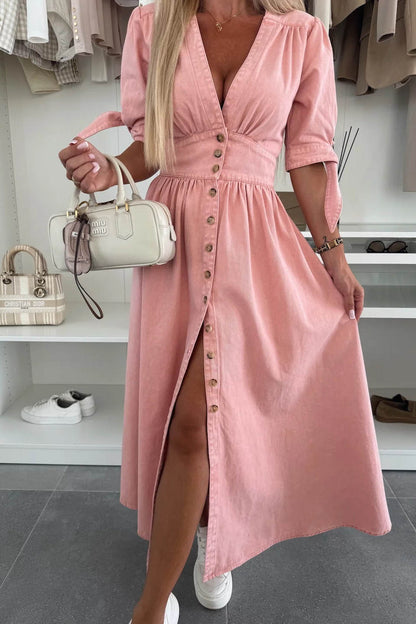 Pink - Woman wearing a light blue denim-look midi dress with a V-neck, button-down front, and tie-detail short sleeves, styled with trainers and a small white handbag.