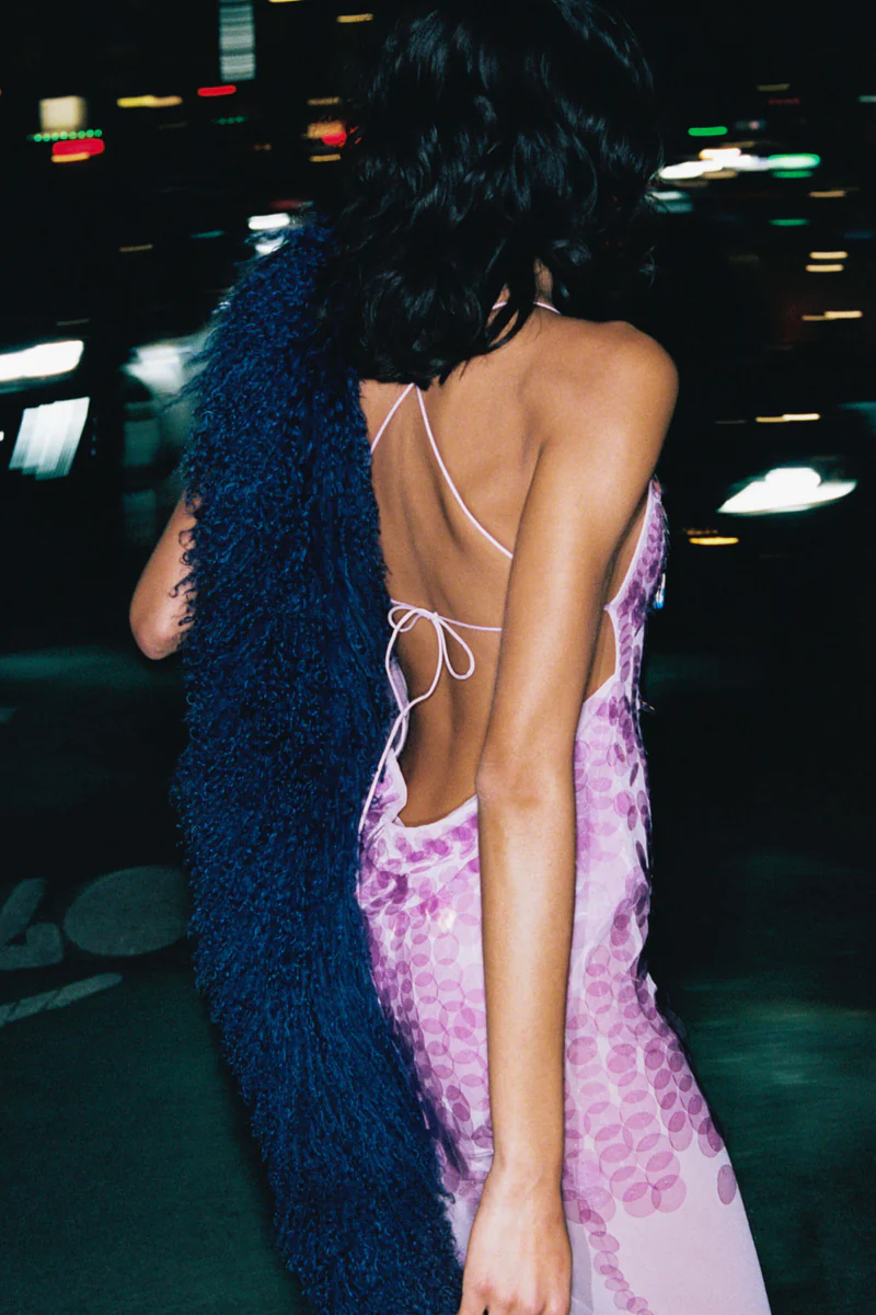 Pink - A model wearing a women's sheer pink maxi dress featuring a plunging V-neckline, delicate straps, and large sequin embellishments cascading down the bodice.