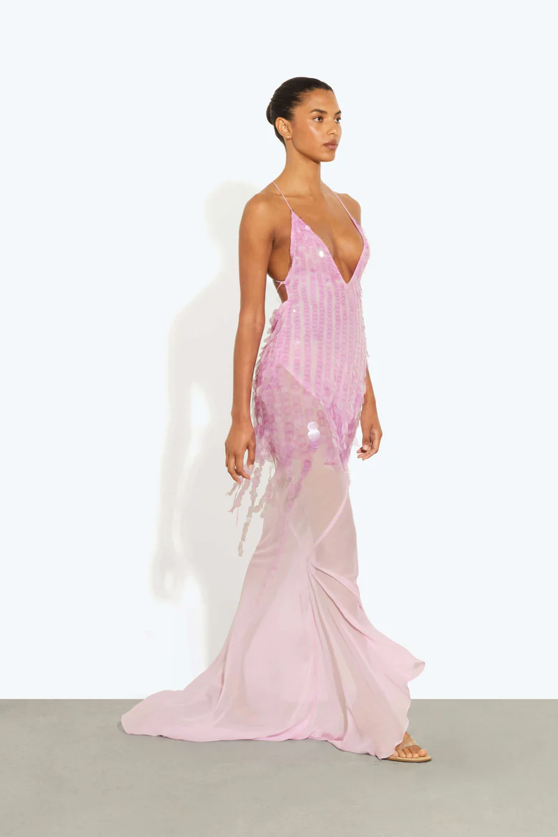 Pink - A model wearing a women's sheer pink maxi dress featuring a plunging V-neckline, delicate straps, and large sequin embellishments cascading down the bodice.