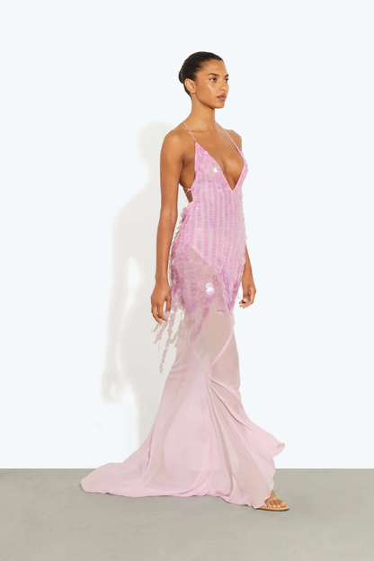 Pink - A model wearing a women's sheer pink maxi dress featuring a plunging V-neckline, delicate straps, and large sequin embellishments cascading down the bodice.