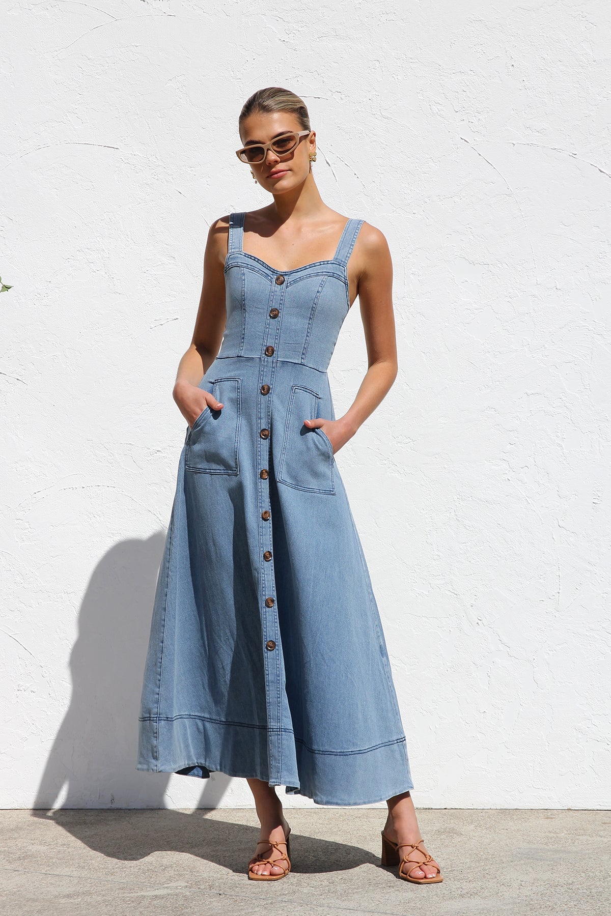 Women's blue structured midi dress featuring a full button-front, wide straps, sweetheart neckline, and front patch pockets.