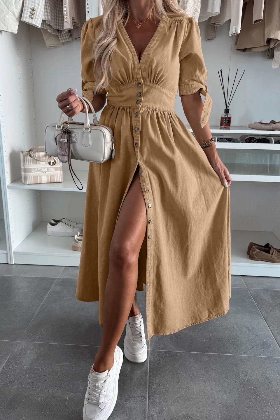 Black - Woman wearing a light blue denim-look midi dress with a V-neck, button-down front, and tie-detail short sleeves, styled with trainers and a small white handbag.