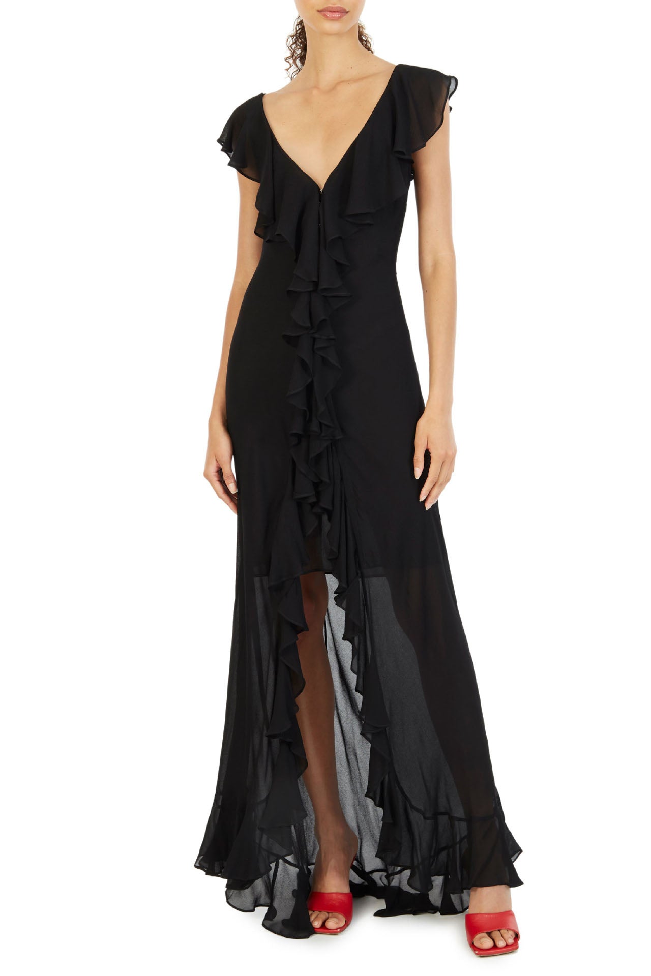 Orange - A woman models an elegant, flowing maxi dress featuring a bold floral print, plunging V-neckline, cascading ruffle details down the front, and a high thigh slit.