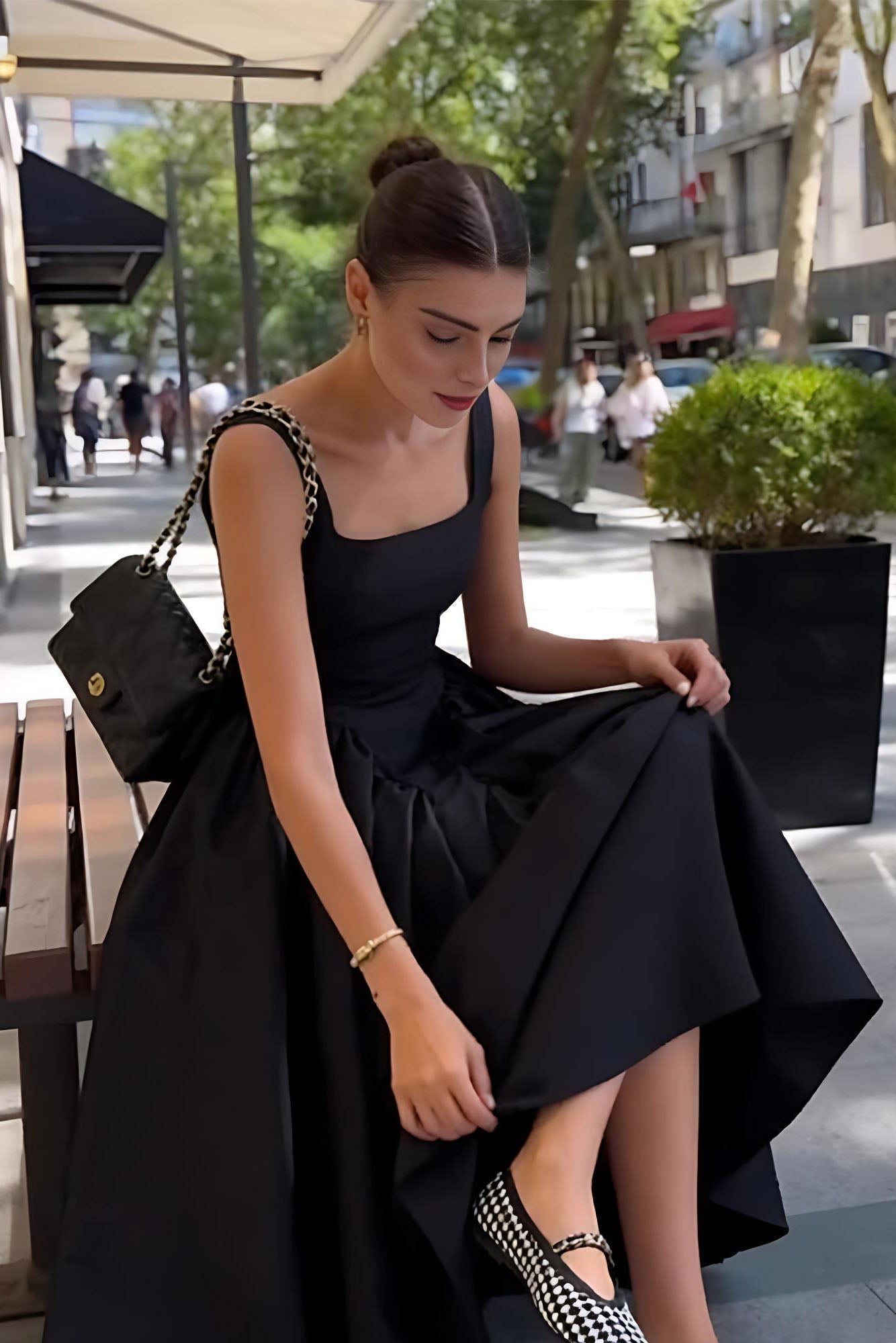 Black - A woman walking outdoors wearing an elegant black sleeveless midi dress featuring a square neckline, fitted bodice, and a full gathered skirt with a dropped waist.
