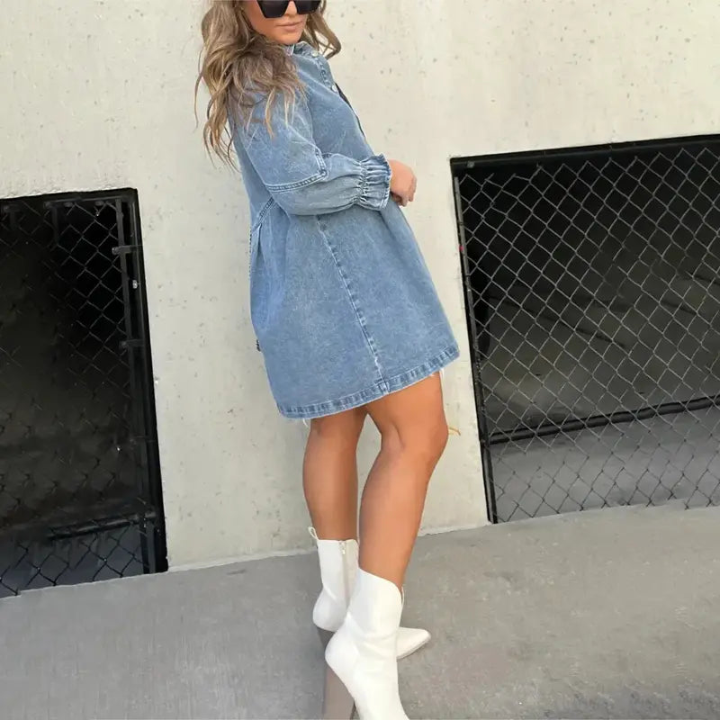 Women's light blue denim mini shirt dress featuring a collar, silver button-down front, and three-quarter sleeves with ruched, flared cuffs.