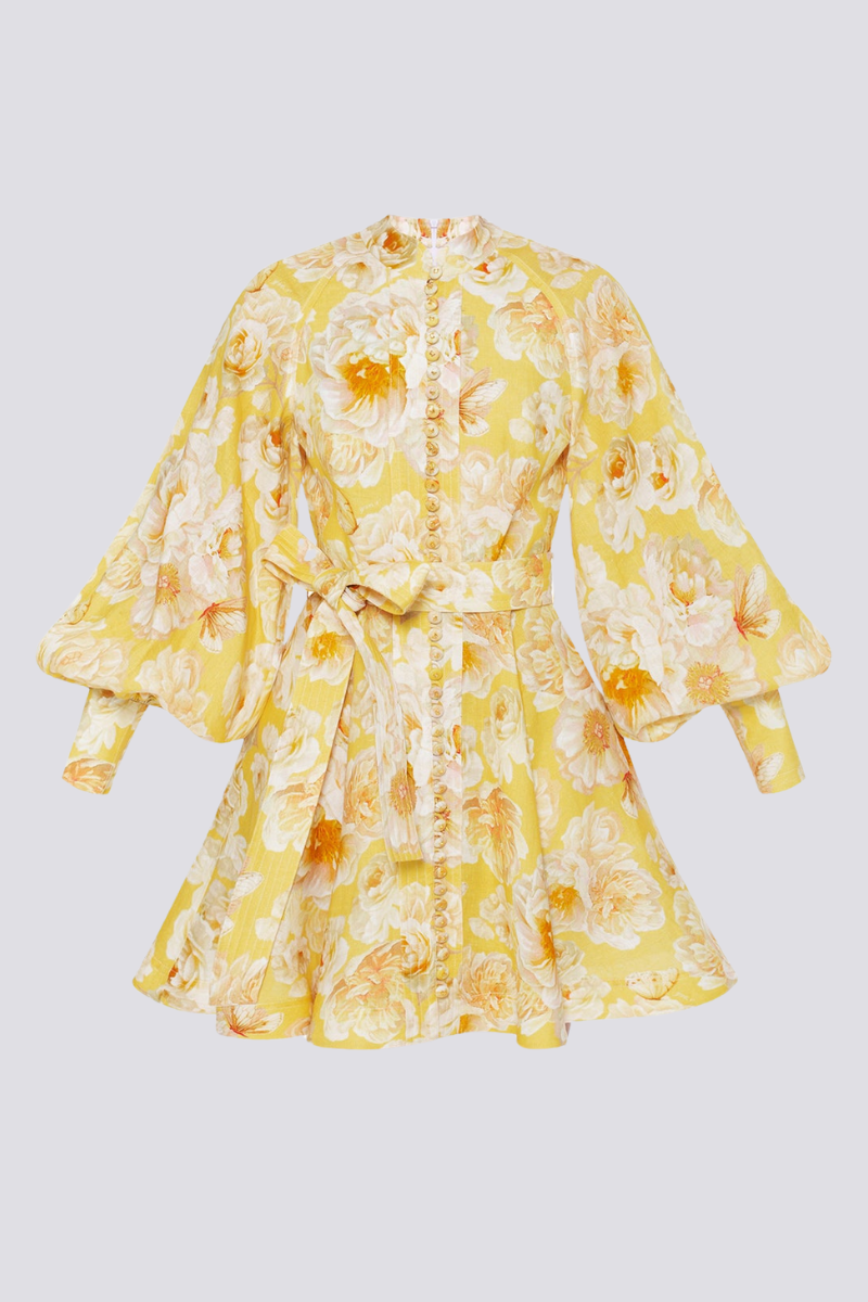 Yellow - A woman wearing a yellow mini dress with a large white floral print, featuring long balloon sleeves, a high neckline with button detailing, and a waist tie belt.