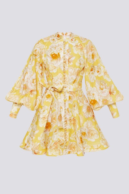 Yellow - A woman wearing a yellow mini dress with a large white floral print, featuring long balloon sleeves, a high neckline with button detailing, and a waist tie belt.