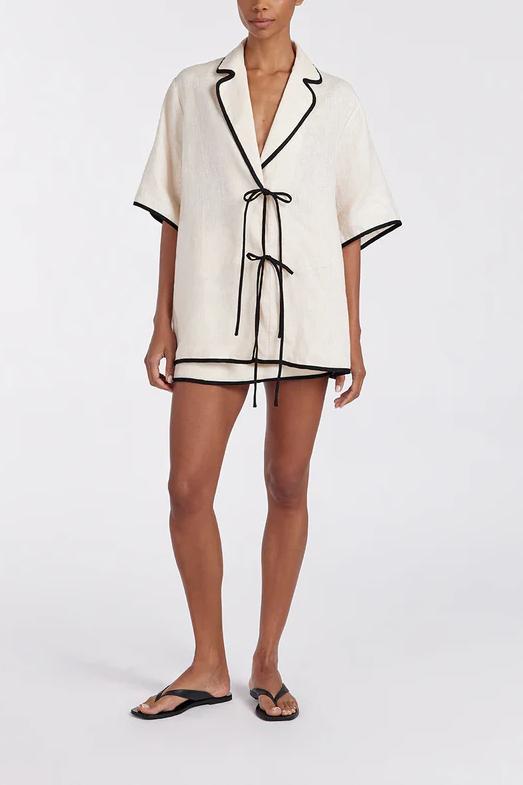Women's relaxed fit short-sleeve shirt featuring a notched lapel collar, double tie-front fastening, and dark contrast piping.