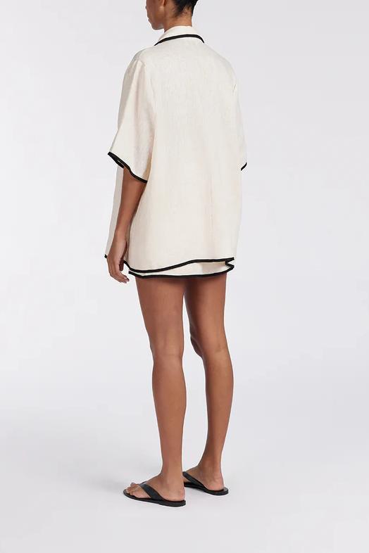 Women's relaxed fit short-sleeve shirt featuring a notched lapel collar, double tie-front fastening, and dark contrast piping.