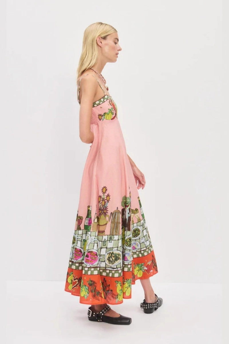 Pink - A model wearing a pink strappy A-line midi dress featuring a vibrant, illustrative novelty print of a dining table, hearts, and checkered borders.