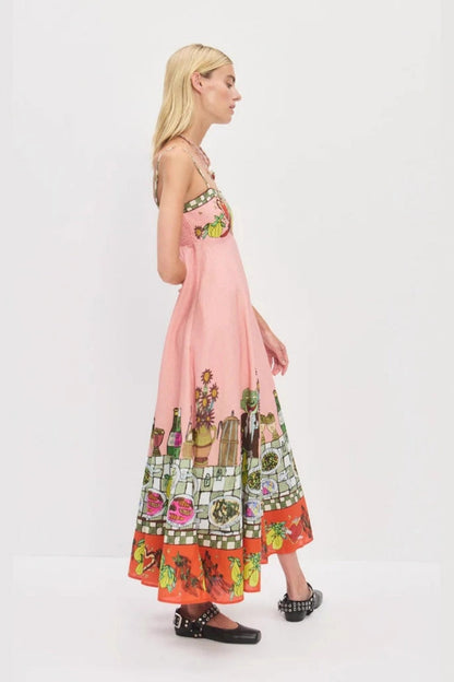 Pink - A model wearing a pink strappy A-line midi dress featuring a vibrant, illustrative novelty print of a dining table, hearts, and checkered borders.
