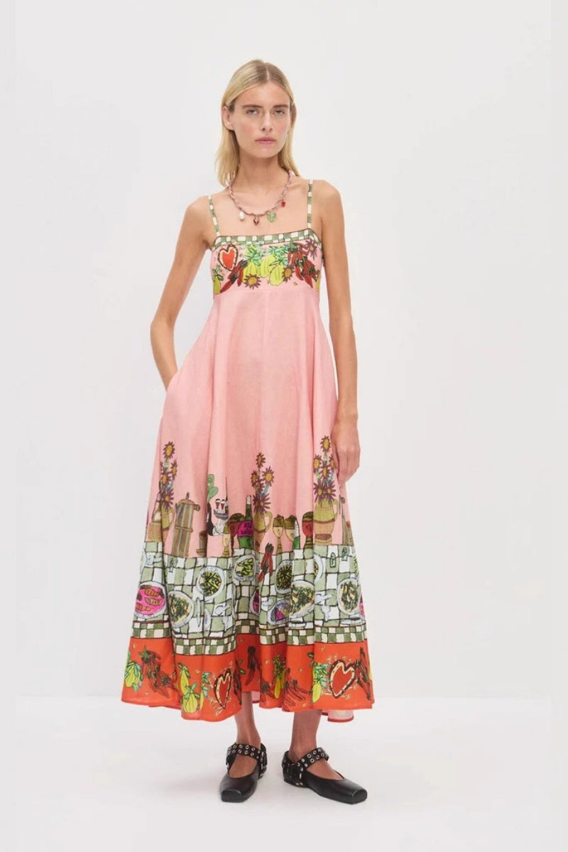 Pink - A model wearing a pink strappy A-line midi dress featuring a vibrant, illustrative novelty print of a dining table, hearts, and checkered borders.