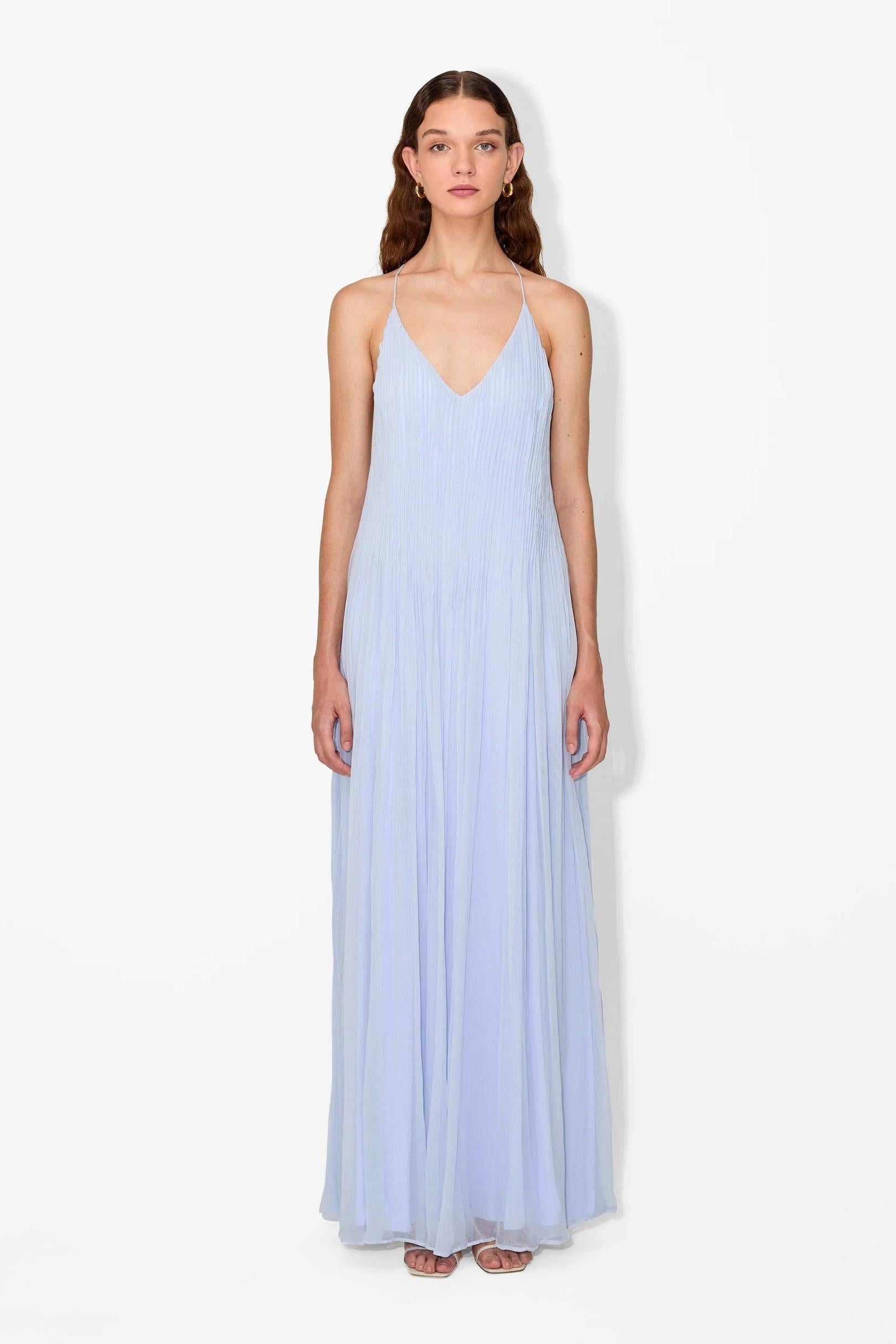 Hydrangea - Front view of a woman modelling a light blue, floor-length pleated maxi dress featuring a V-neckline and thin straps.