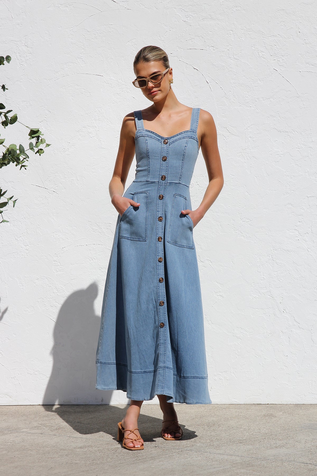 Women's blue structured midi dress featuring a full button-front, wide straps, sweetheart neckline, and front patch pockets.