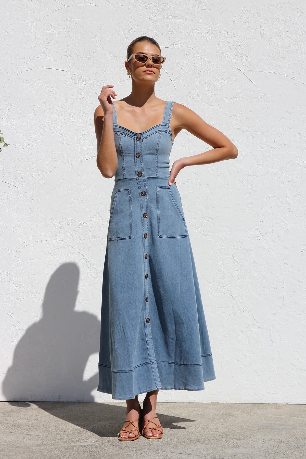 Women's blue structured midi dress featuring a full button-front, wide straps, sweetheart neckline, and front patch pockets.