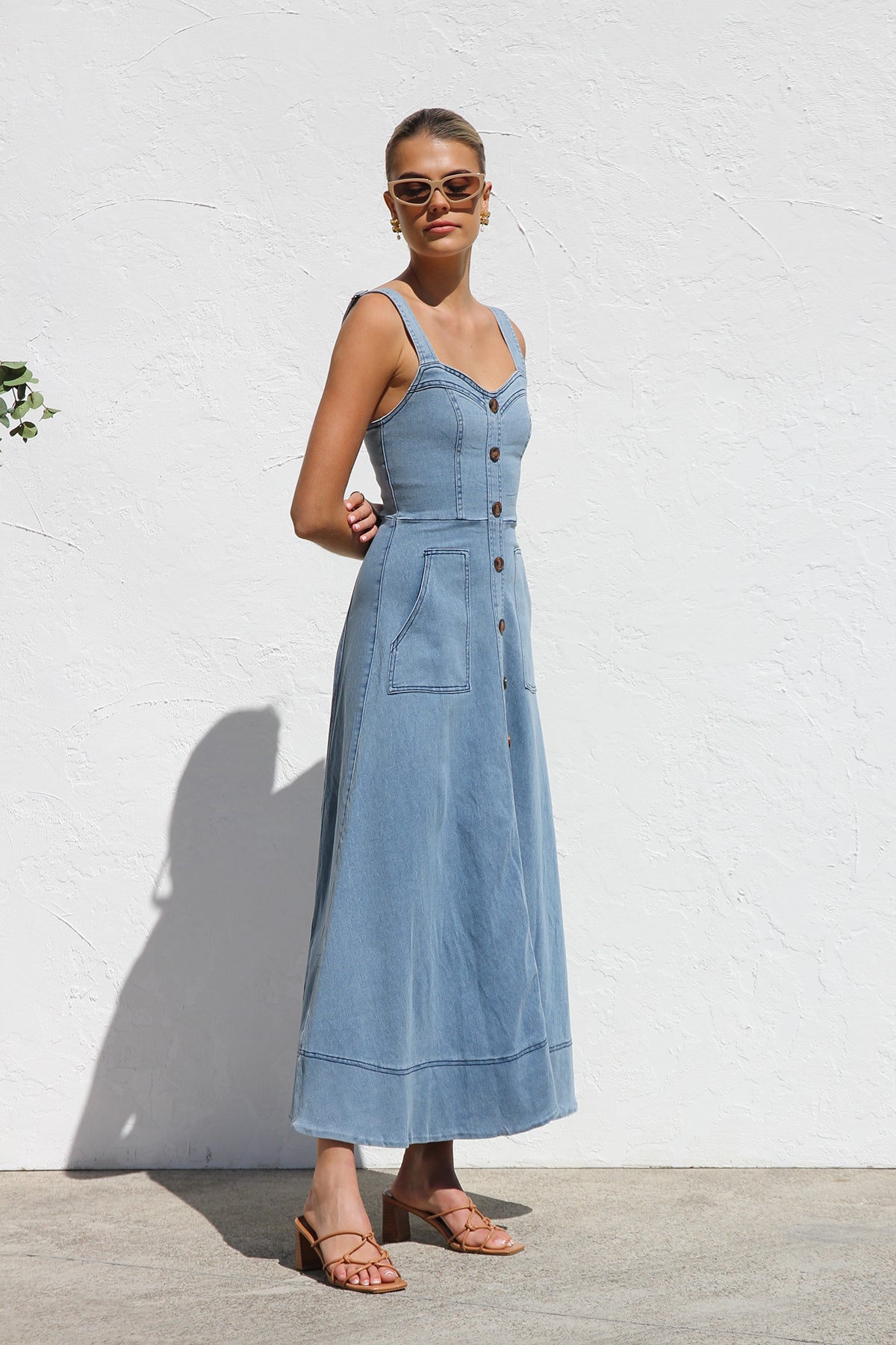 Women's blue structured midi dress featuring a full button-front, wide straps, sweetheart neckline, and front patch pockets.