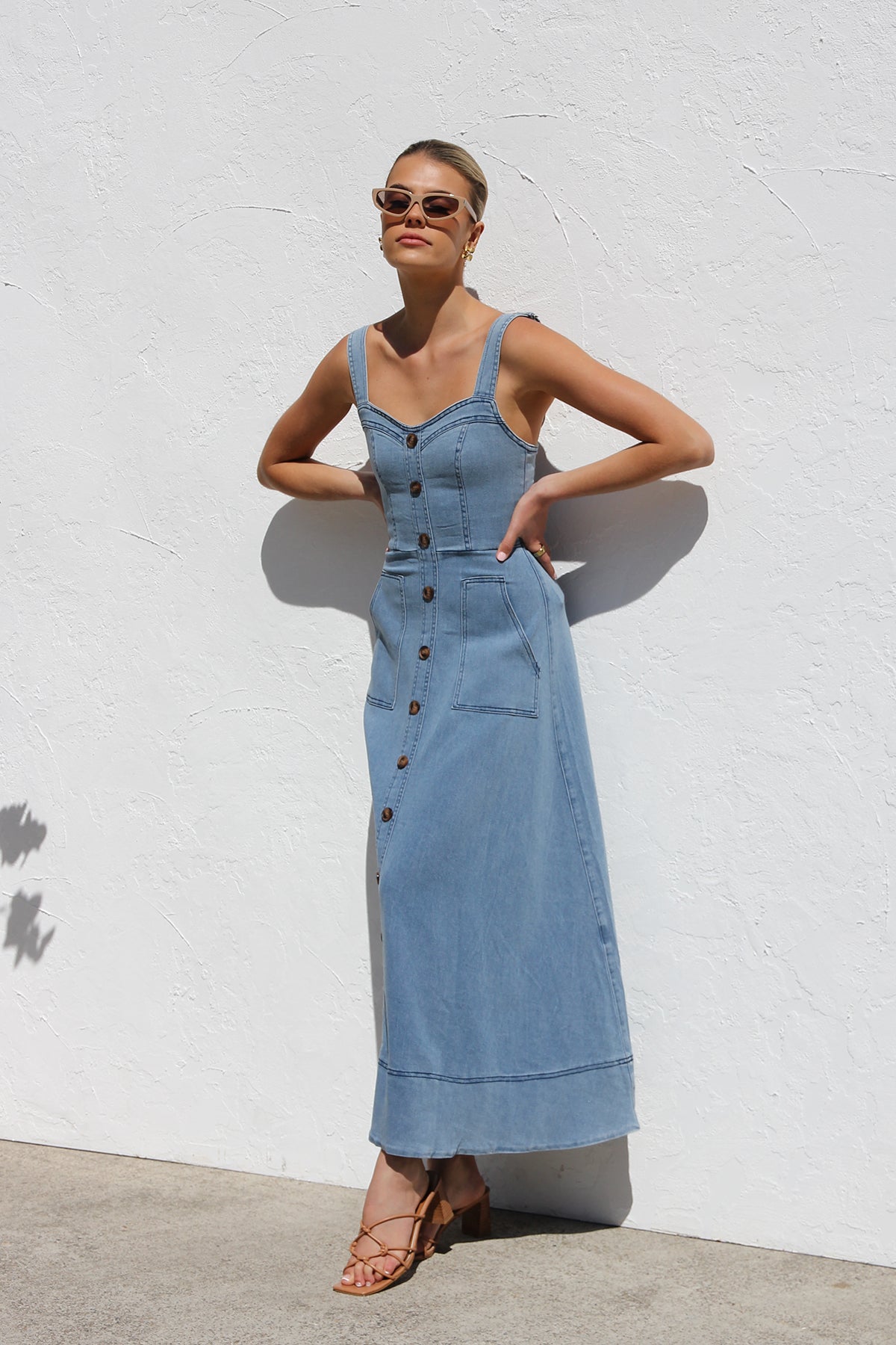 Women's blue structured midi dress featuring a full button-front, wide straps, sweetheart neckline, and front patch pockets.