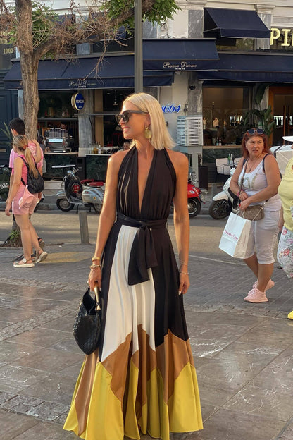 Multi - Women wearing an elegant halter neck maxi dress featuring a plunging neckline, wide tie-waist belt, and a flowing A-line skirt with bold black, white, brown, and mustard colour-block panels.