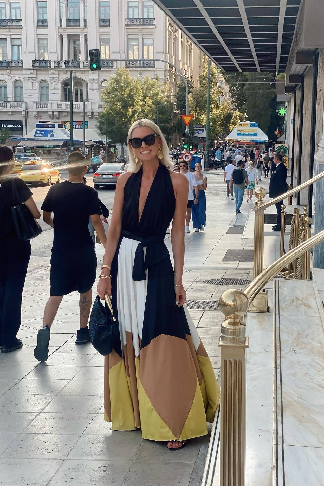 Multi - Women wearing an elegant halter neck maxi dress featuring a plunging neckline, wide tie-waist belt, and a flowing A-line skirt with bold black, white, brown, and mustard colour-block panels.