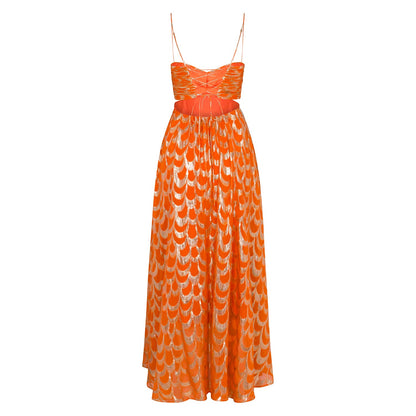 A woman modelling a vibrant orange maxi dress featuring a metallic gold scallop pattern, a ruched sweetheart bodice, side cut-outs, and delicate spaghetti straps.