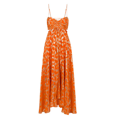 A woman modelling a vibrant orange maxi dress featuring a metallic gold scallop pattern, a ruched sweetheart bodice, side cut-outs, and delicate spaghetti straps.