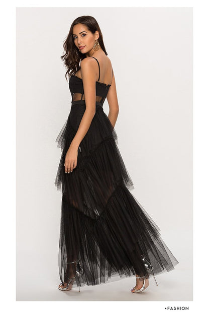 Black - A woman wearing a pale pink, floor-length maxi dress featuring a structured corset-style bodice with sheer panels and a voluminous, multi-tiered tulle skirt.