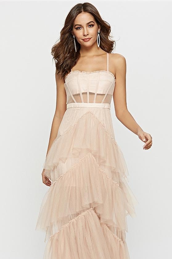 Pink - A woman wearing a pale pink, floor-length maxi dress featuring a structured corset-style bodice with sheer panels and a voluminous, multi-tiered tulle skirt.