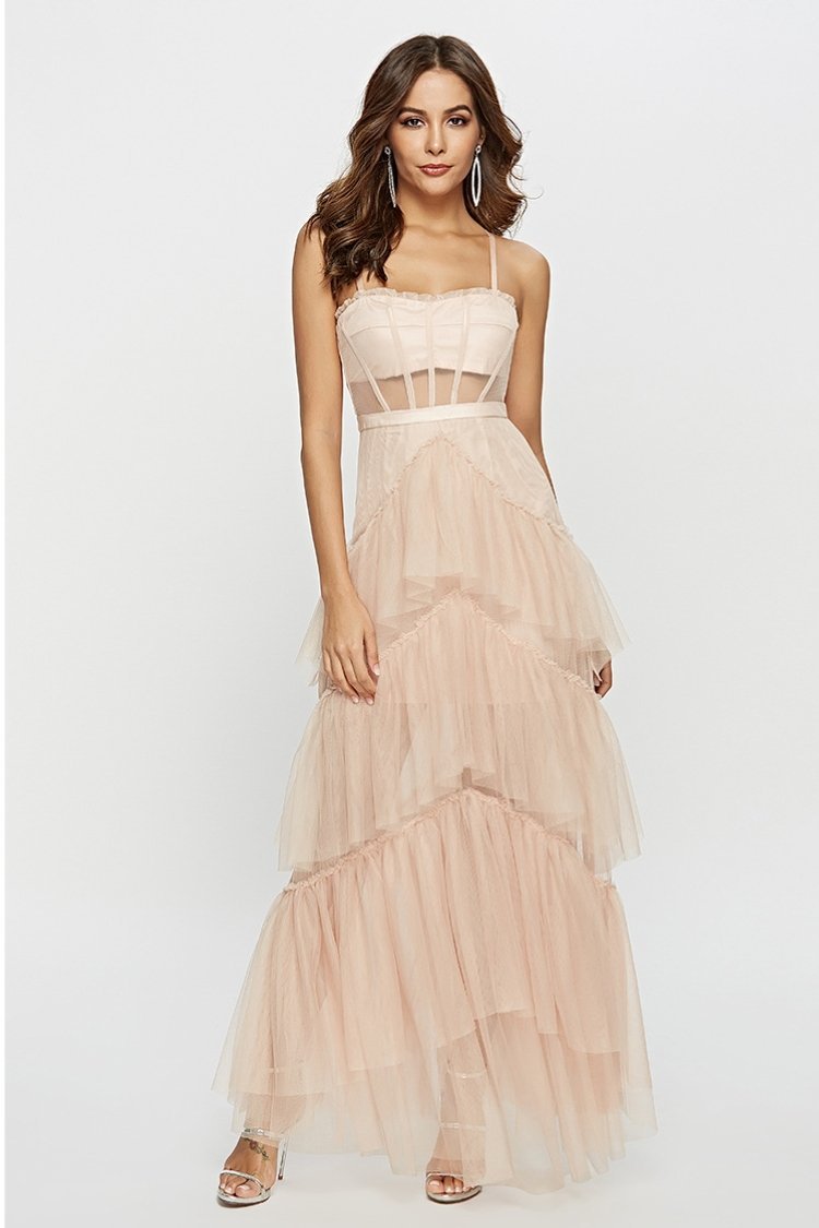 Pink - A woman wearing a pale pink, floor-length maxi dress featuring a structured corset-style bodice with sheer panels and a voluminous, multi-tiered tulle skirt.