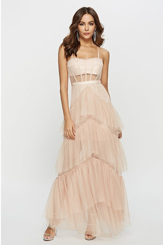 Pink - A woman wearing a pale pink, floor-length maxi dress featuring a structured corset-style bodice with sheer panels and a voluminous, multi-tiered tulle skirt.