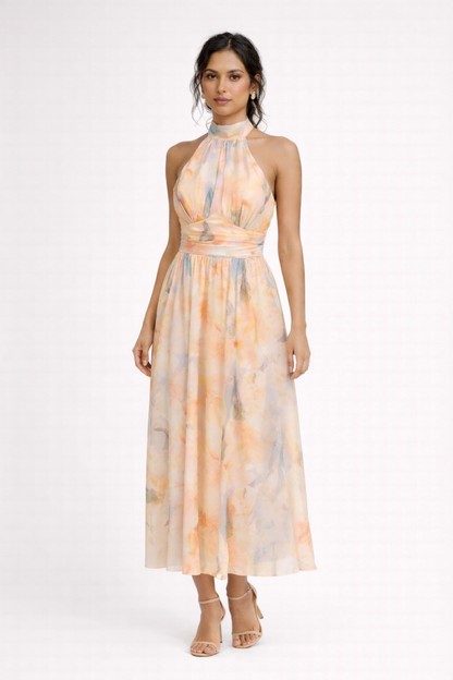 Peach - A model wearing a sleeveless floral halter-neck midi dress with a wide ruched waistband and flowing A-line skirt.