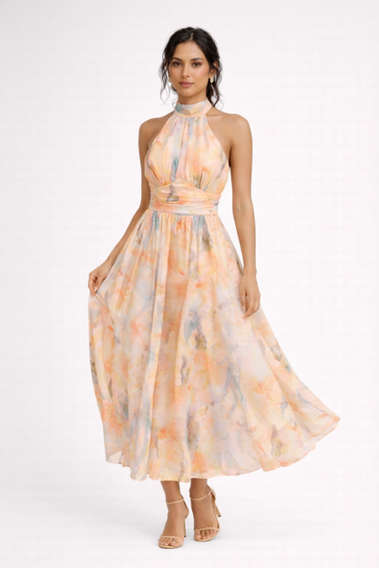 Peach - A model wearing a sleeveless floral halter-neck midi dress with a wide ruched waistband and flowing A-line skirt.
