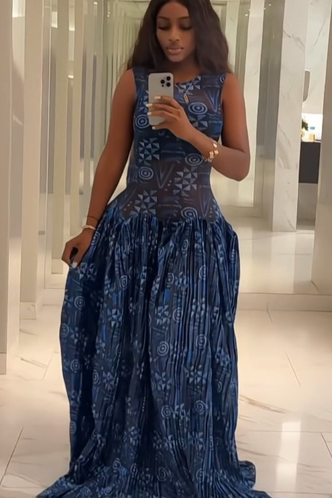 Blue - A woman wearing a sleeveless maxi dress featuring a fitted, semi-sheer geometric bodice and a voluminous gathered skirt with a mixed abstract blue print.