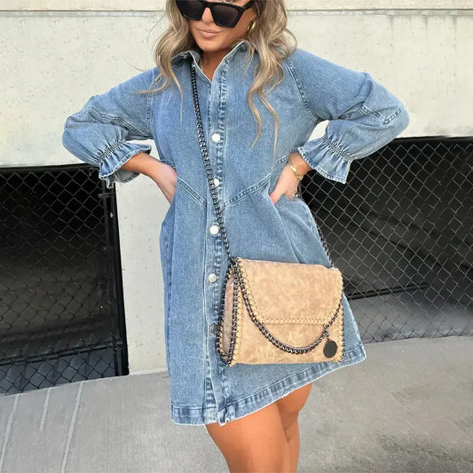Women's light blue denim mini shirt dress featuring a collar, silver button-down front, and three-quarter sleeves with ruched, flared cuffs.