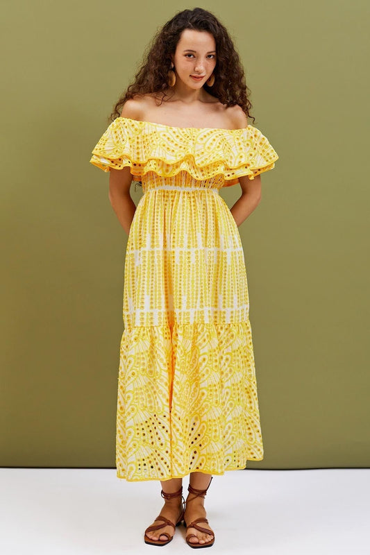Yellow - A woman wearing a yellow and white off-the-shoulder midi dress featuring a smocked bodice, ruffled neckline, tiered skirt, and intricate broderie anglaise cut-out patterns.