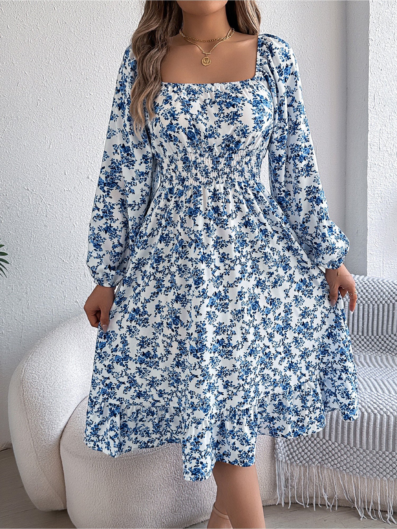 Blue - Woman wearing a floral square-neck midi dress with long sleeves, a shirred waist, and a ruffled hem