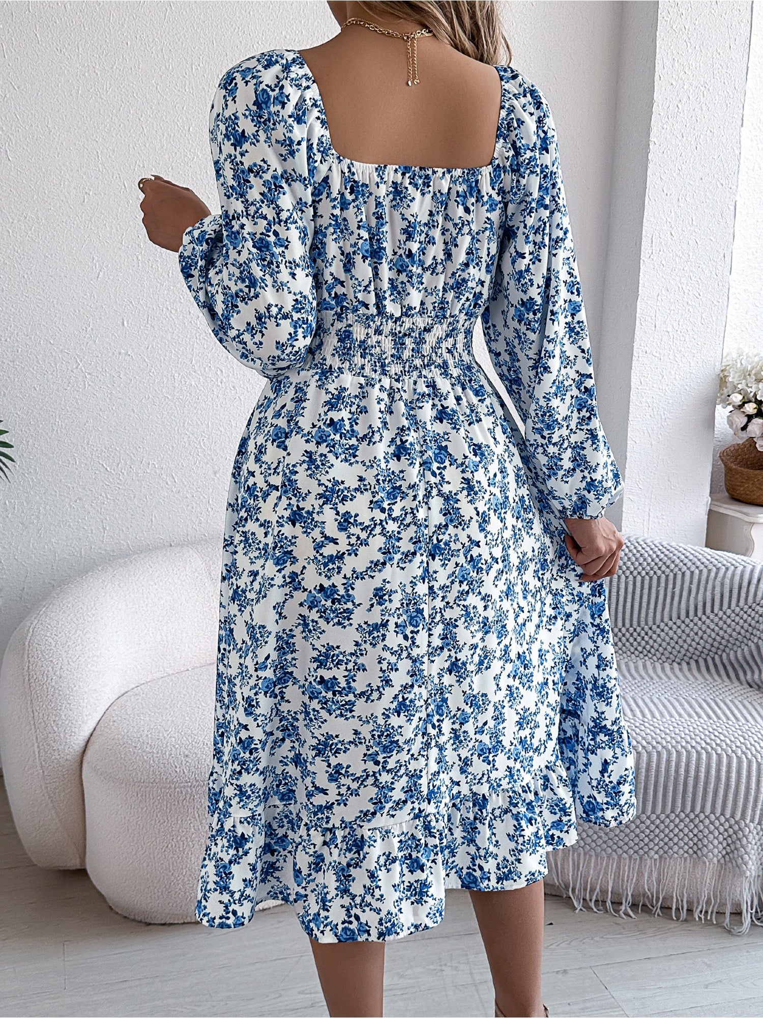 Blue - Woman wearing a floral square-neck midi dress with long sleeves, a shirred waist, and a ruffled hem