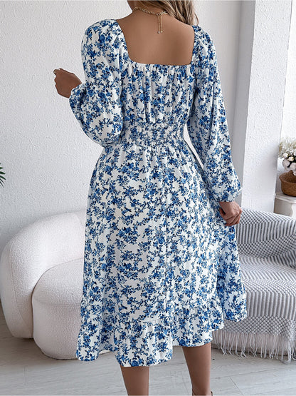 Blue - Woman wearing a floral square-neck midi dress with long sleeves, a shirred waist, and a ruffled hem