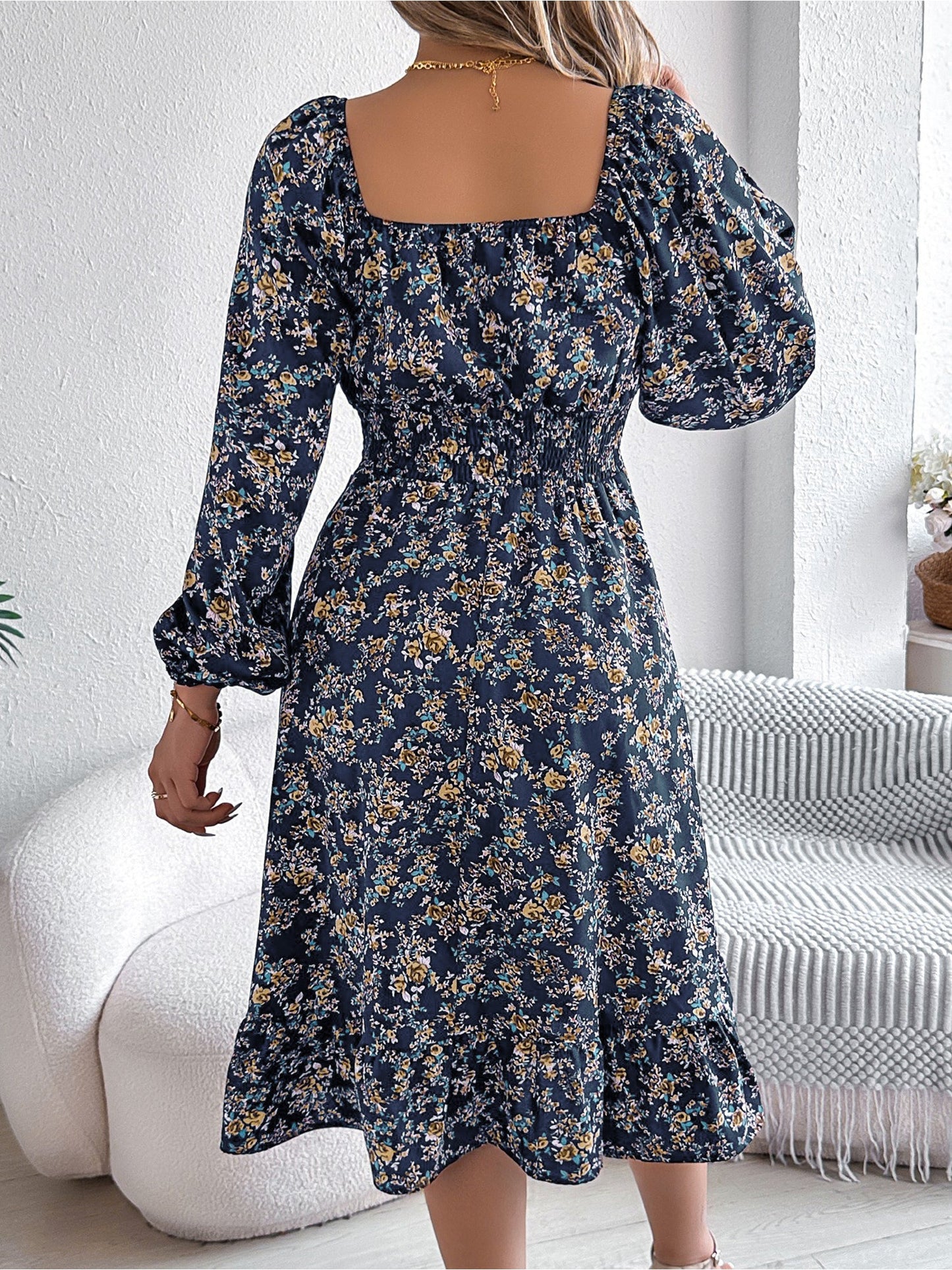 Navy - Woman wearing a floral square-neck midi dress with long sleeves, a shirred waist, and a ruffled hem