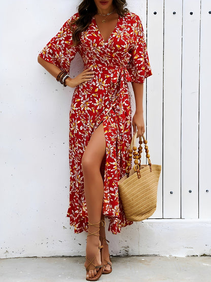 Red - Model wearing a floral V-neck wrap maxi dress with short sleeves and a waist tie, styled with a woven tote bag and sandals.
