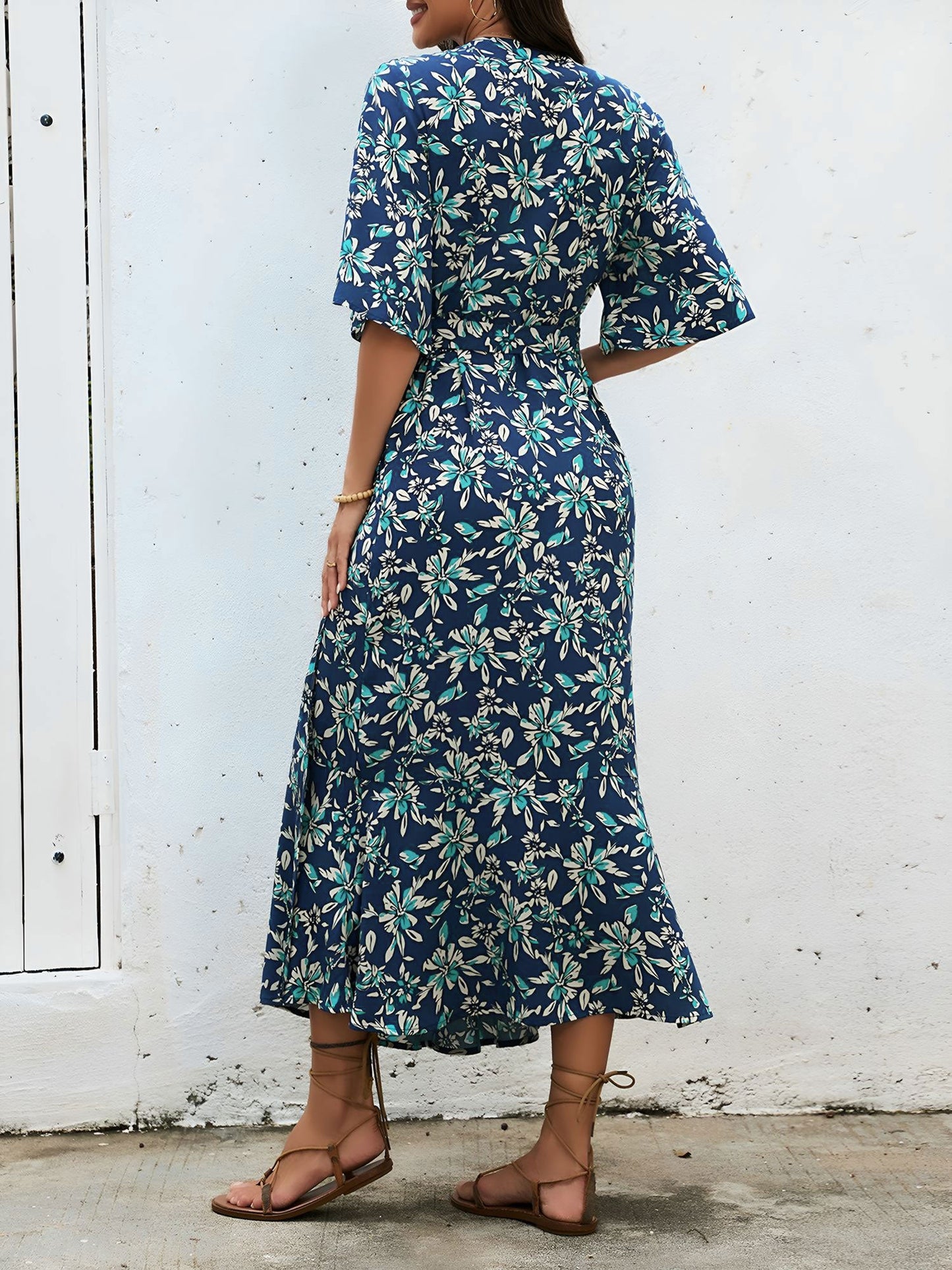 Navy Blue - Model wearing a floral V-neck wrap maxi dress with short sleeves and a waist tie, styled with a woven tote bag and sandals.