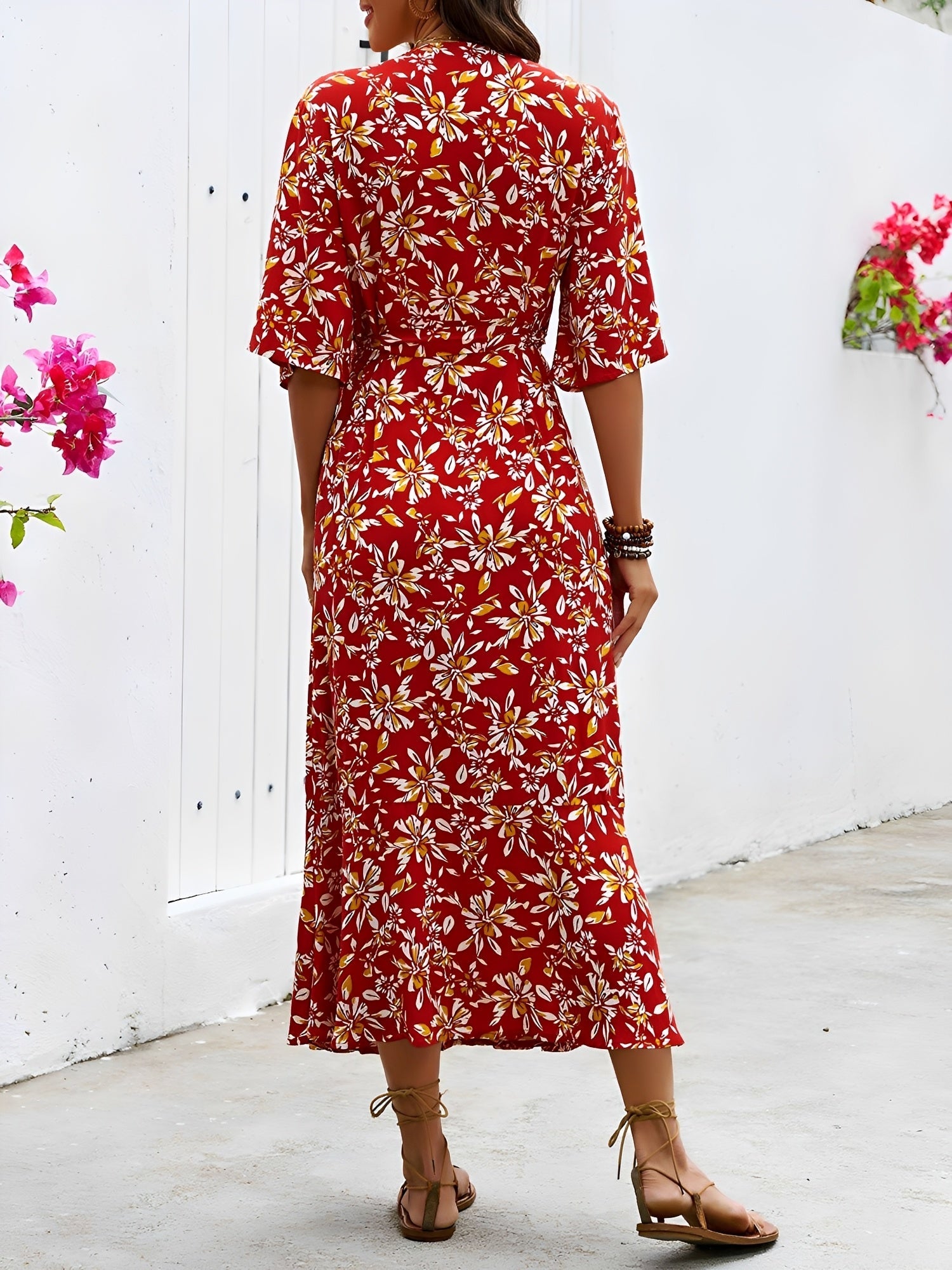 Red - Model wearing a floral V-neck wrap maxi dress with short sleeves and a waist tie, styled with a woven tote bag and sandals.