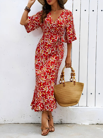 Red - Model wearing a floral V-neck wrap maxi dress with short sleeves and a waist tie, styled with a woven tote bag and sandals.