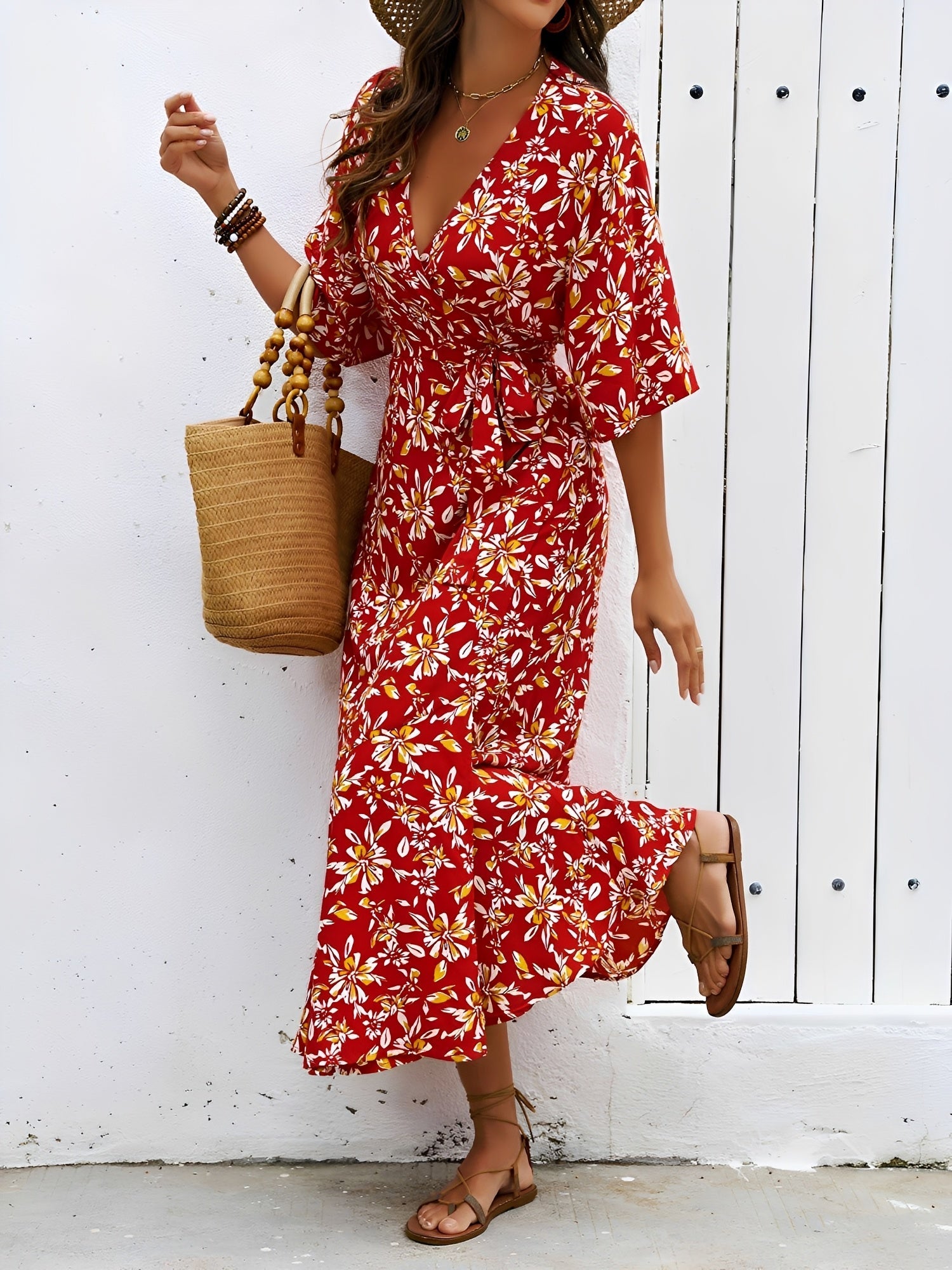 Red - Model wearing a floral V-neck wrap maxi dress with short sleeves and a waist tie, styled with a woven tote bag and sandals.