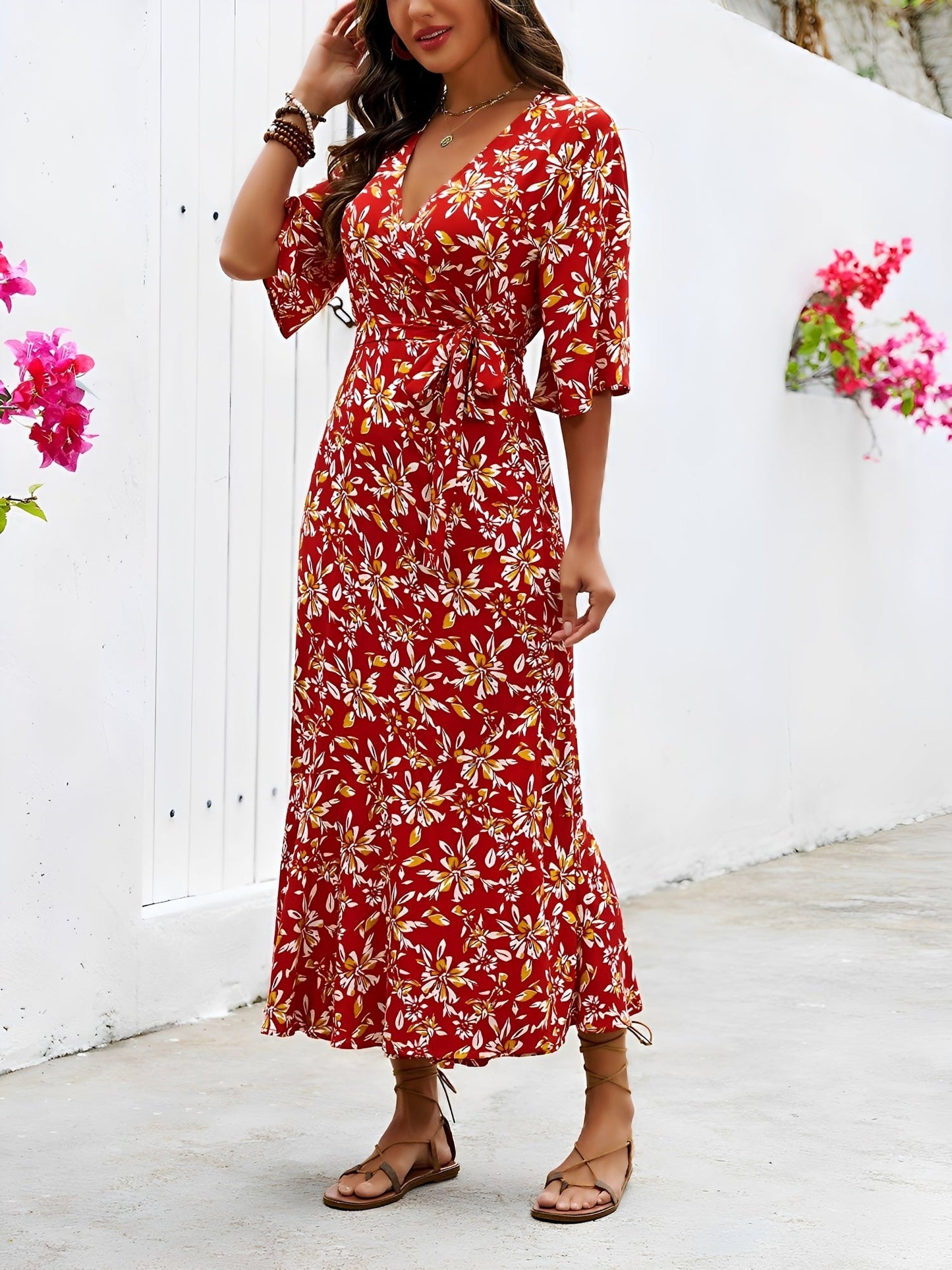 Red - Model wearing a floral V-neck wrap maxi dress with short sleeves and a waist tie, styled with a woven tote bag and sandals.
