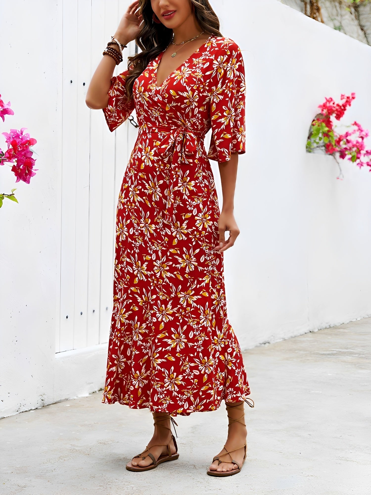 Red - Model wearing a floral V-neck wrap maxi dress with short sleeves and a waist tie, styled with a woven tote bag and sandals.