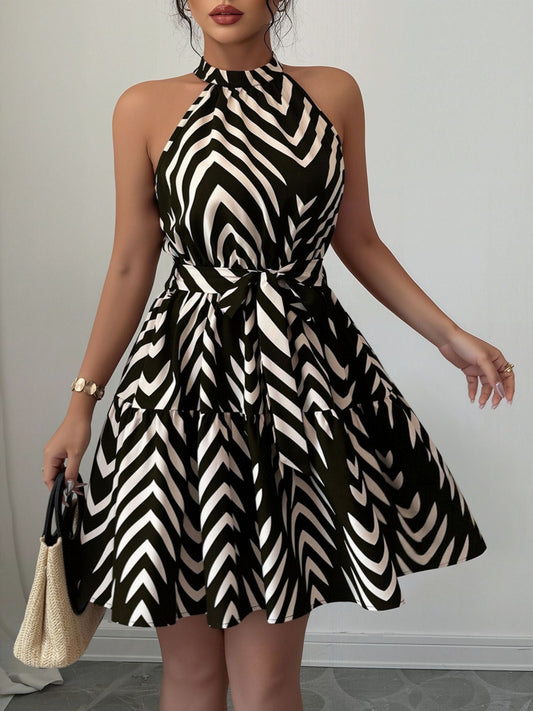 Black - Woman wearing a geometric patterned halter-neck mini dress with a tie waist and tiered skirt.