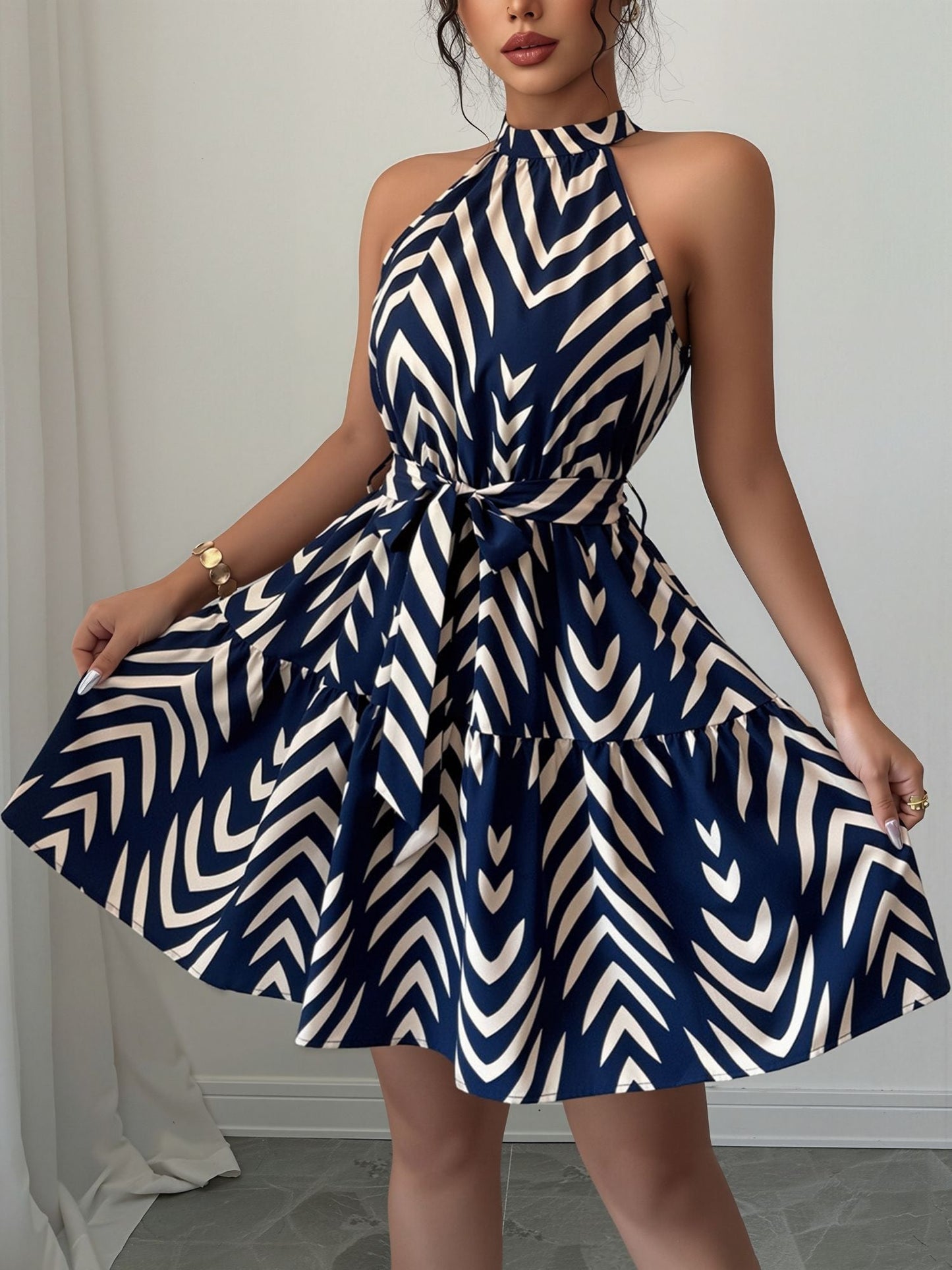 Blue - Woman wearing a geometric patterned halter-neck mini dress with a tie waist and tiered skirt.
