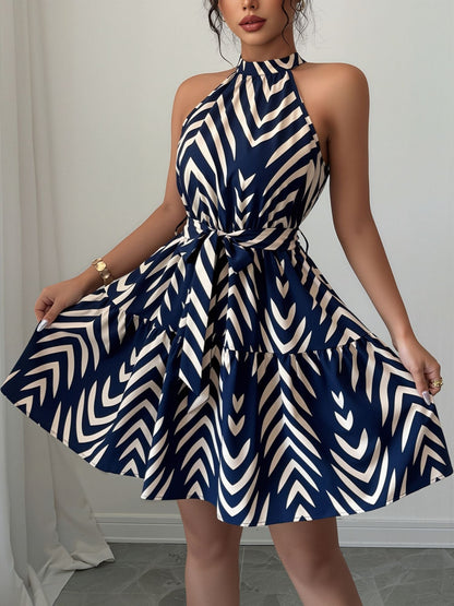 Blue - Woman wearing a geometric patterned halter-neck mini dress with a tie waist and tiered skirt.