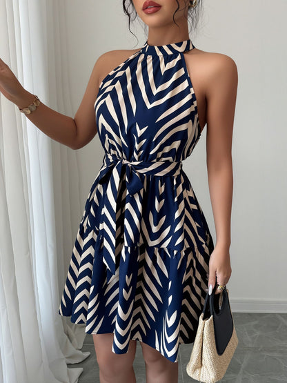 Blue - Woman wearing a geometric patterned halter-neck mini dress with a tie waist and tiered skirt.