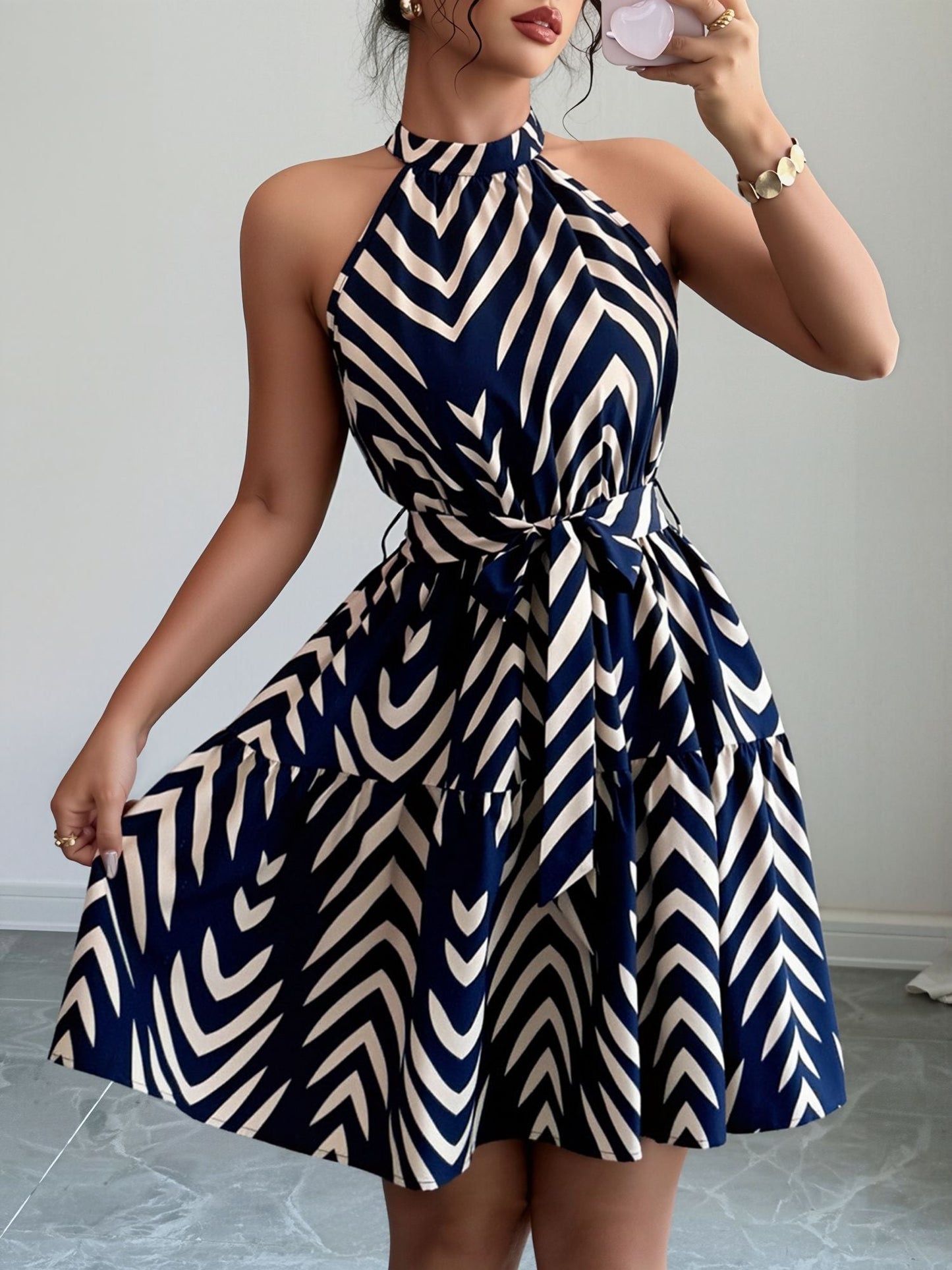 Blue - Woman wearing a geometric patterned halter-neck mini dress with a tie waist and tiered skirt.